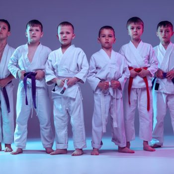 group-of-boys-children-training-martial-arts-karate-isolated-over-purple-studio-background-in-neon